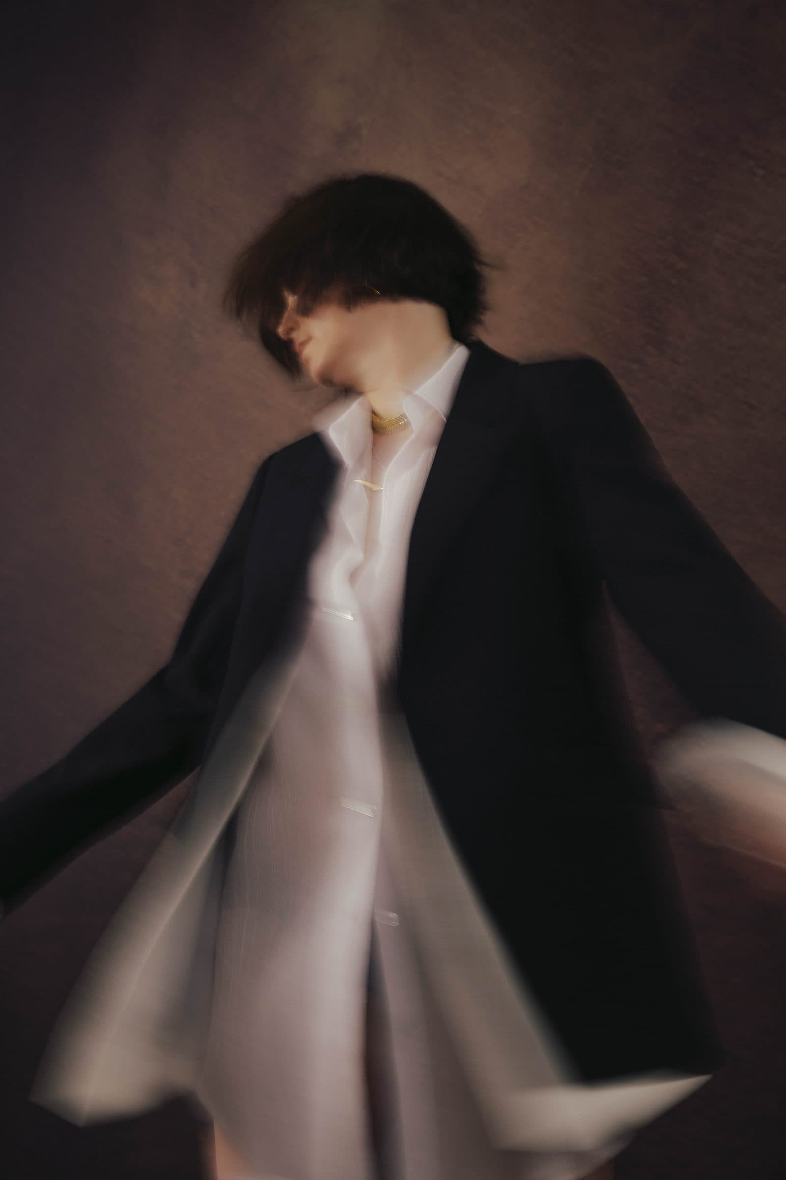 Woman caught mid-turn, her dress and blazer in motion, a dynamic editorial portrait at Body & Soul Studios, London.